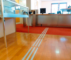 Photo showing a corduroy tactile guidance strip on the floor leading to the reception desk